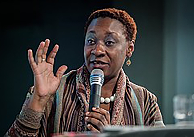 Maisha Auma hält ein Mikrofon und spricht